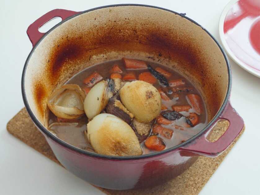 Wild game pot roast braising in stock inside a Dutch oven