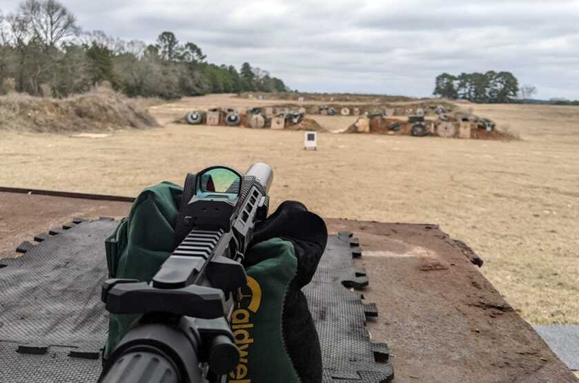 AR pistol positioned for the walk-out method while zeroing a red dot sight