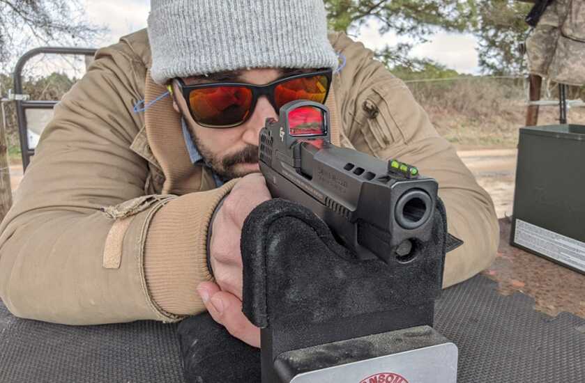 Firearm supported on a solid shooting rest while sighting in a red dot optic