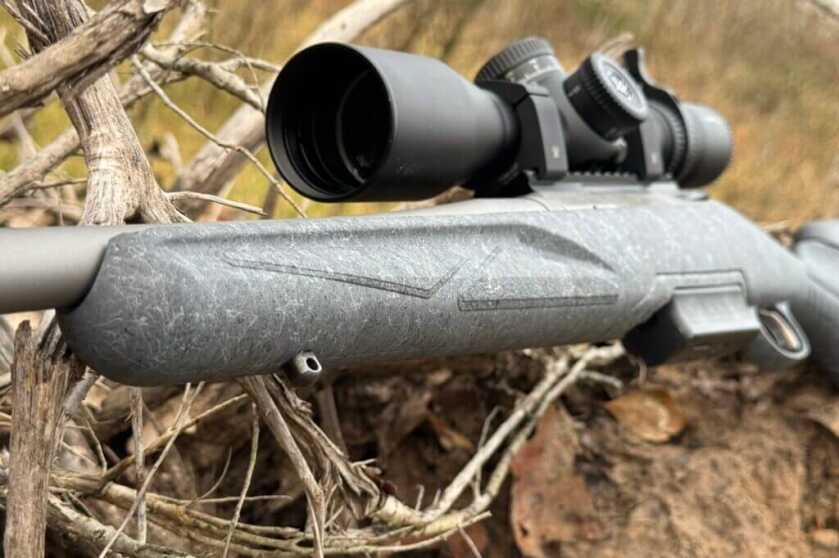 Ruger Rifle with scope sitting in dry leaves