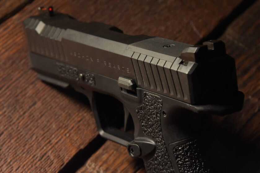 Glamour shot of a black handgun on a wooden table. 