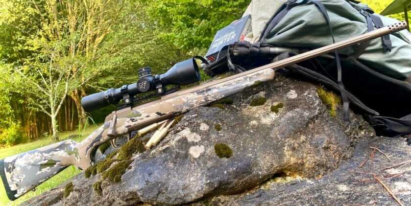 X-Bolt Speed SR with factory muzzle brake installed&nbsp;propped on large rocks with gear bag and ammmunition