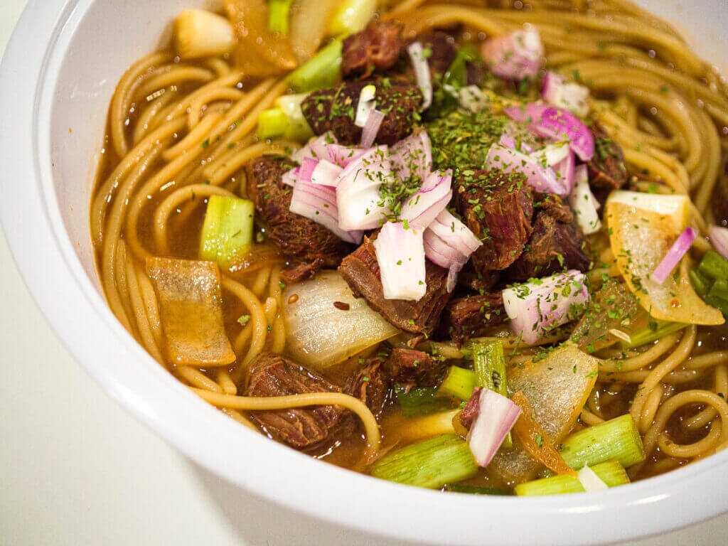 Finished soup in a bowl with noodles and meat.