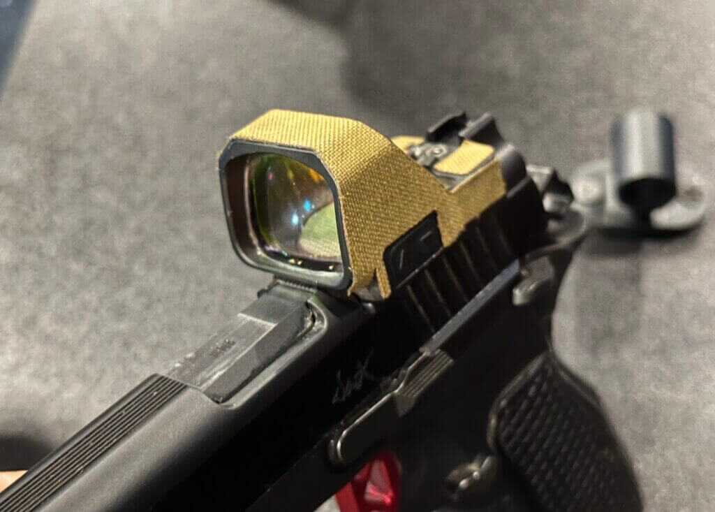 A pistol optic with a large window sits on top of the handgun.