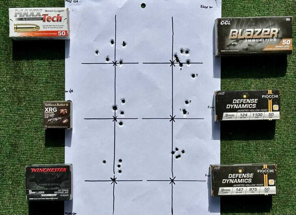 shooting target lays on a tabletop, with several boxes of ammunition laid out next to it.