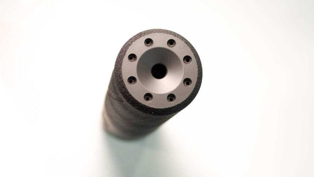 Close up of the exit-end of the suppressor standing on a table.