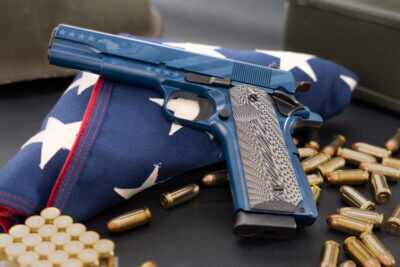 Chiappa 1911 Field Special 250th Independence Edition .45 ACP pistol displayed on a folded American flag with ammunition.