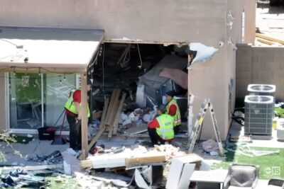 Investigators examine severe damage after a vehicle crashed through the wall of an Arizona home before a fatal shooting.