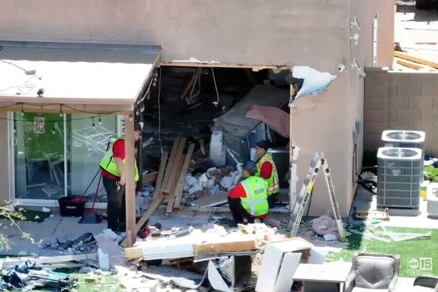 Investigators examine severe damage after a vehicle crashed through the wall of an Arizona home before a fatal shooting.