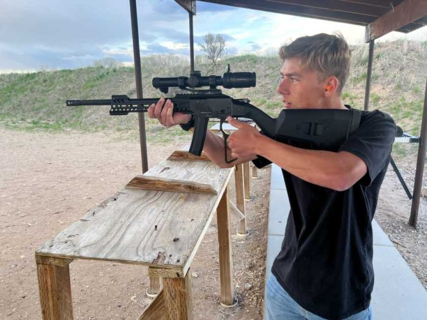 POF Tombstone 9mm with the action being worked by a young man shooting off hand. He is looking through the scope while working the action.