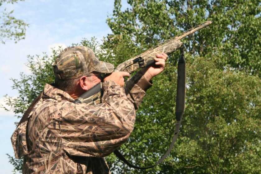Down Gauging: The Beretta A-400 Extreme Plus Semi-Automatic 20-Gauge Hunter in camo aiming the Beretta A-400 at the trees above him