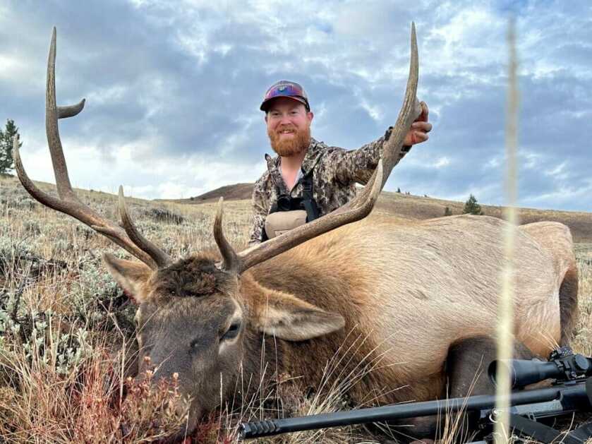 3 - Fireside Stories: How I Killed My Smallest Bull Elk on The Best Tag I've Ever Had - Part 3 of 3 A hunter in camo poses with his bull elk.