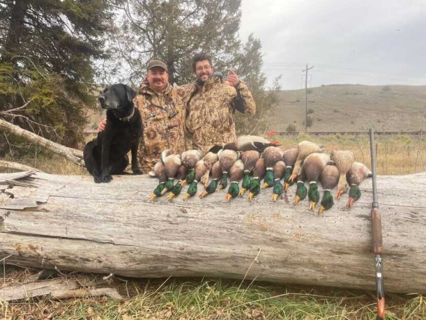 3-December-Kryptek Flyway Deadzone Review Hunters dressed in Kryptek with their hunting dog, 20-gauge shotgun, and a huge pile of duck mallards
