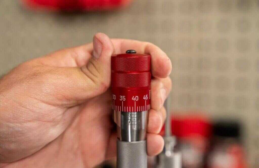 A man holding the click-adjust bullet seating micrometer.