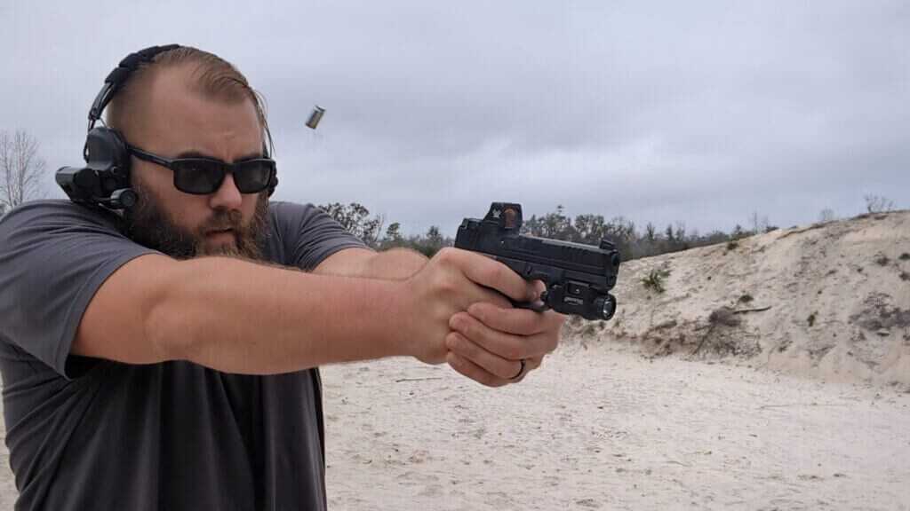 Man with glasses and hearing protection shooting semi-automatic handgun