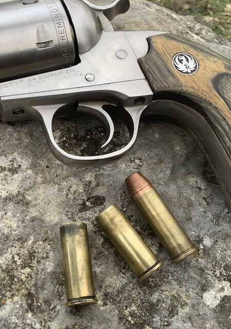 handgun resting on a rock with cutting edge bullets