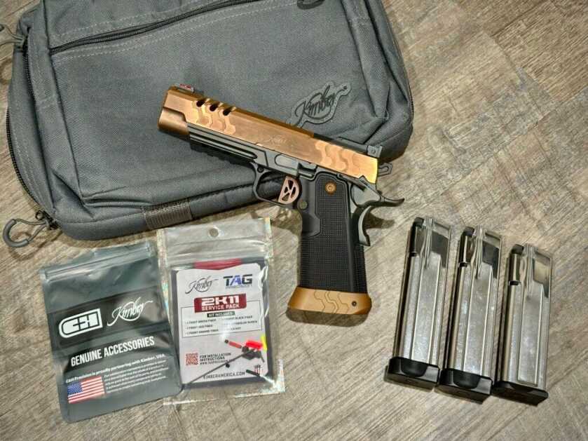 A bronze 2011 pistol is shown with three magazines and optics-mounting hardware