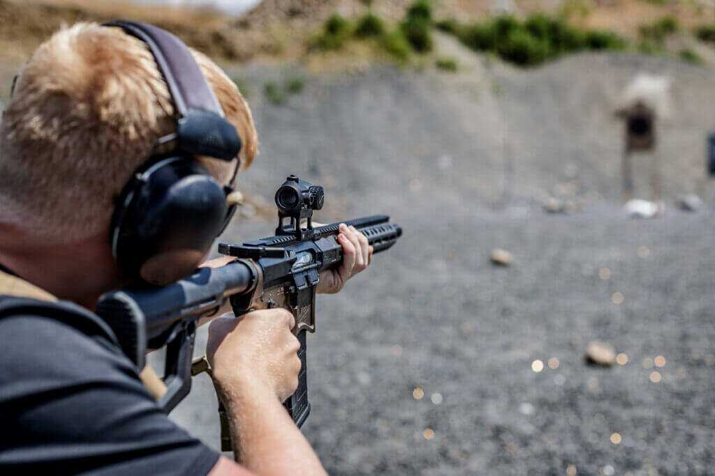 mans shooting rifle with optic at a target 