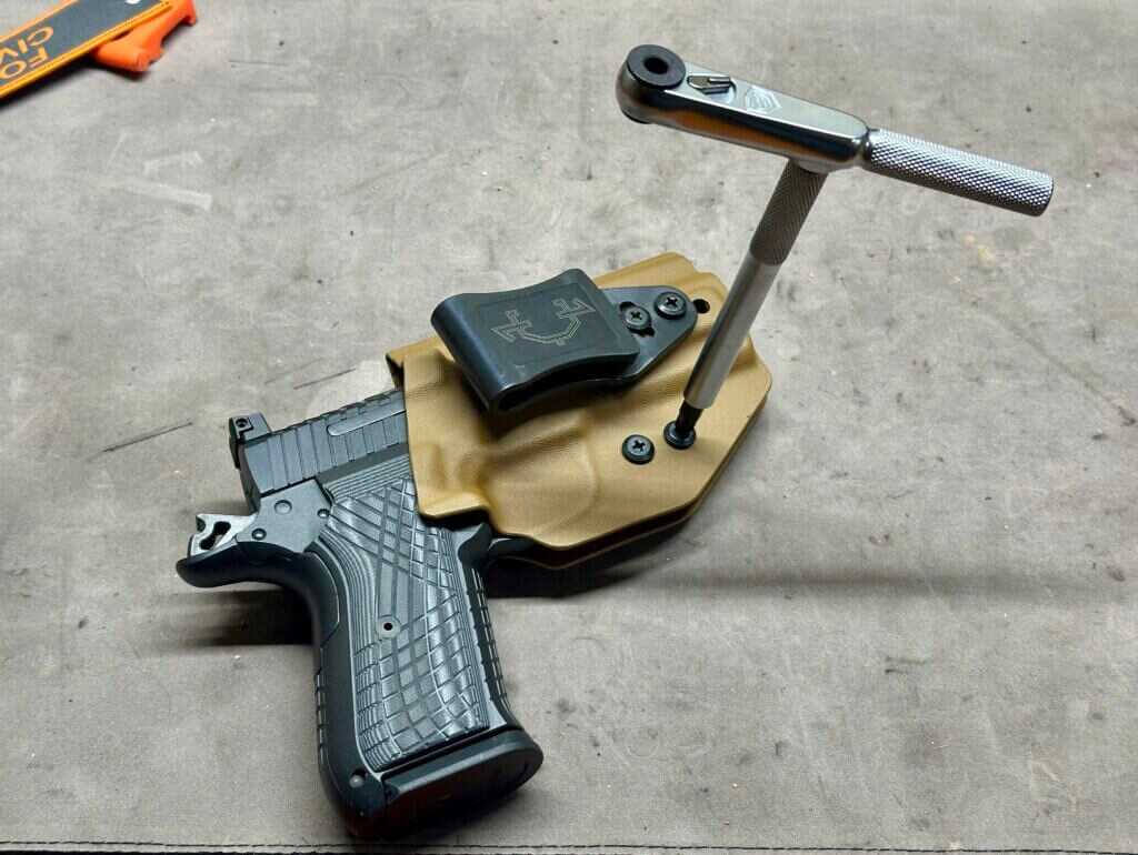 Using a T-handle wrench to tighten a brown pistol holster's retention screws. 