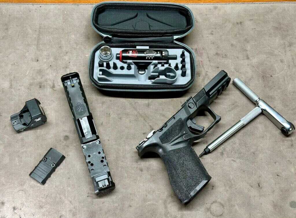 A disassembled pistol lays on a mat where it is being worked on with the Smart-Torq wrench and driver laying next to it.