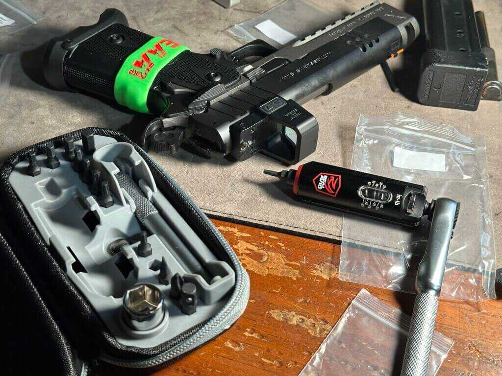 A handgun and tool set are laid out on a work bench. Witness2311 Match X