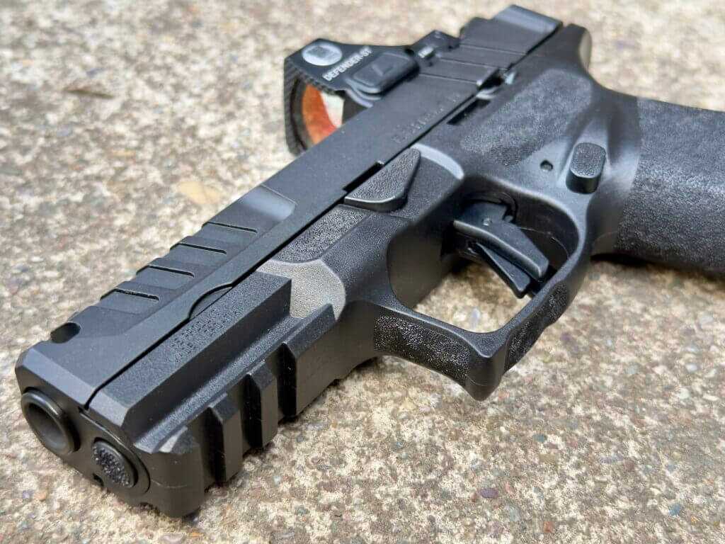Closeup of a black handgun on concrete.