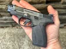 A small handgun is positioned in the palm of a man's hand.