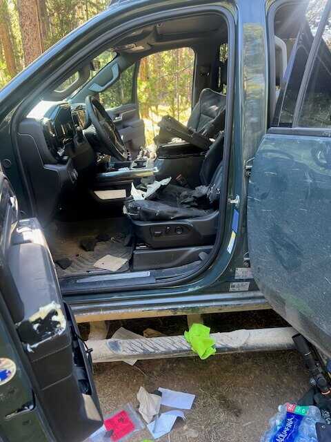 Interior wide shot showing shredded seats, ripped console, and debris after black bear feeding