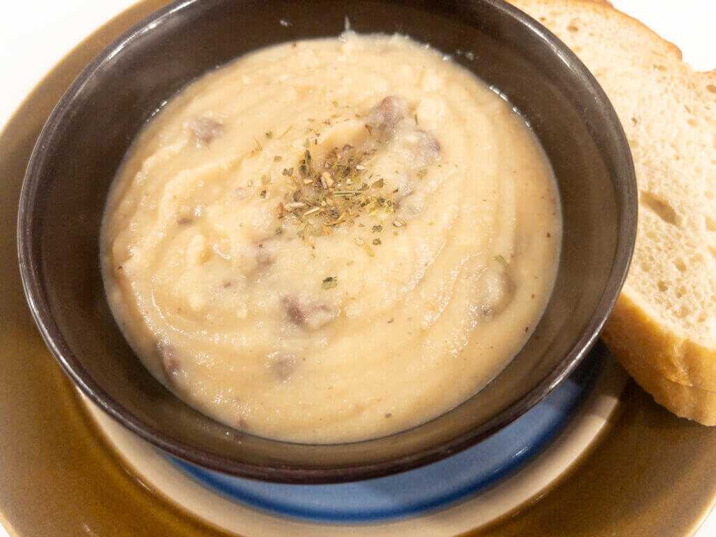 Close up overhead photo of elk heart mashed potato soup in a bowl with bread.