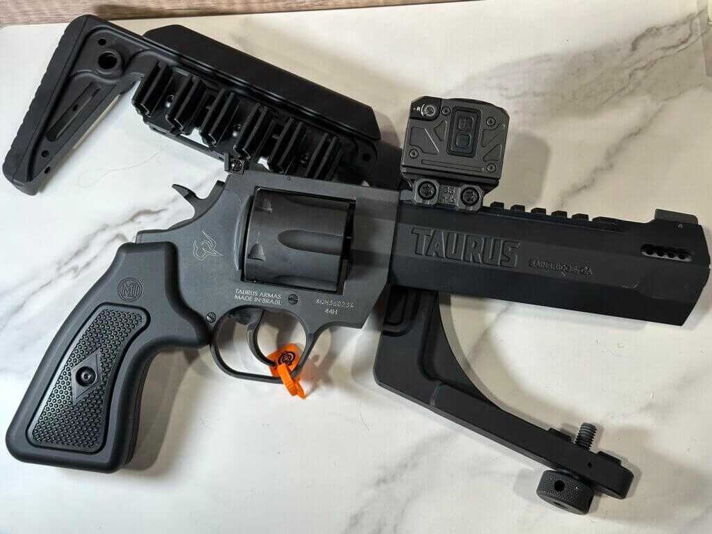 A revolver is laying on top of a removable buttstock. both lay on a white granite background.