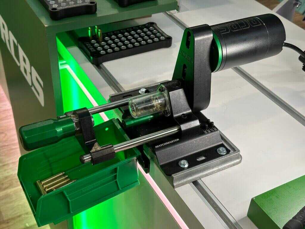 There is a green and black machine that is bolted to a white table.