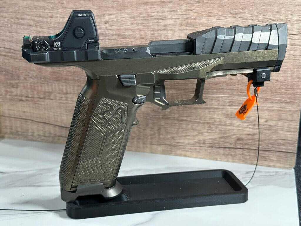 A green and black pistol rests on a display stand.