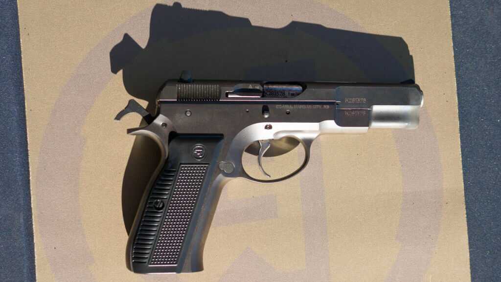 The whole gun lyingo n a table facing right with the right side up. There is a strong shadow cast above the gun.