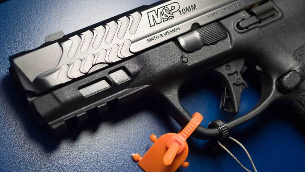 Close up view of the front left side of the gun laying on a blue table with the gun facing left.