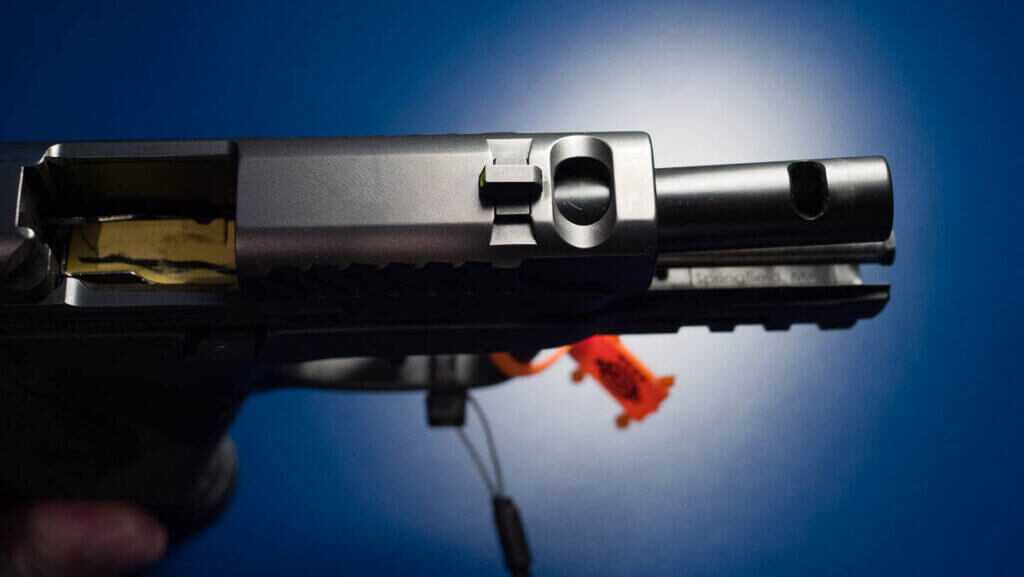 Close up view of the front top side of the gun wioth the slide retracted to show both the ported slide and the ported barrel.