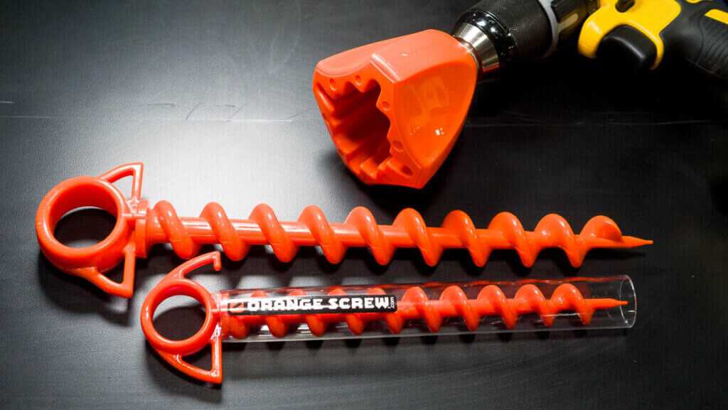 Close up of the two screws in two sizes on a black table top with the drill adapter shown, too.