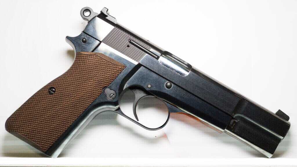 The SA-35 standing on a ledge against a white display, grip corner and barrel resting on the flat surface.