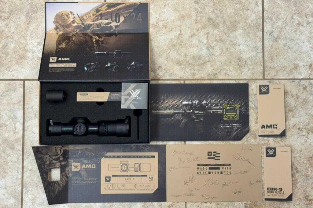 Vortex AMG 1-10x24 review package contents with signed authenticity documents, flip caps, battery, and included accessories