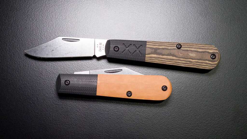 Two knives on a black table, one folded and one open.