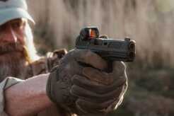 A man shooting a pistol with the Steiner MP5-C red dot on it.