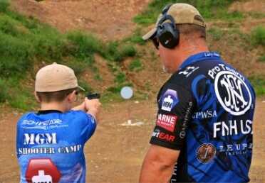 Kids And Guns: Teach Your Children Well Larry Houk, working with a youngster on pistol shooting skills and safety.