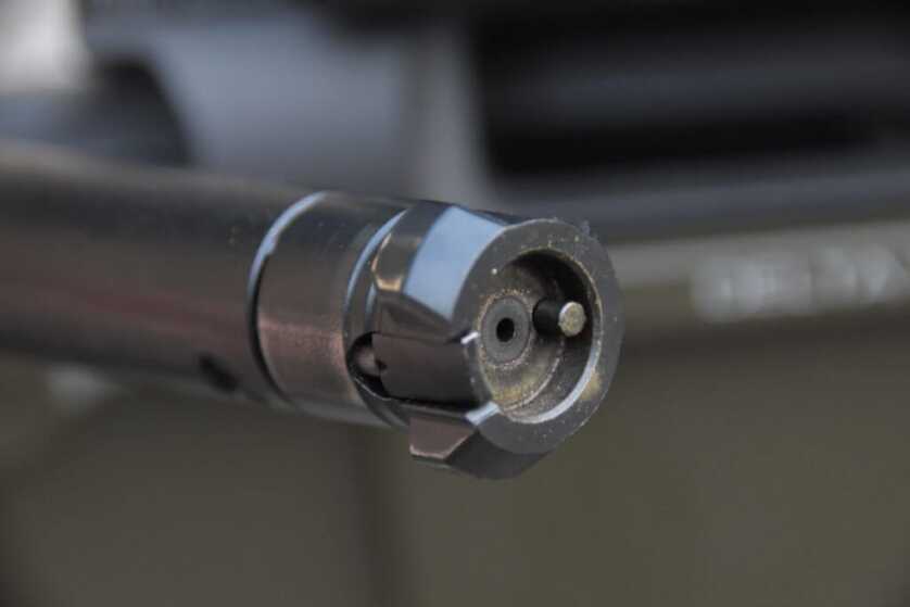 The dirty bolt face of a three-lug rifle bolt is shown.