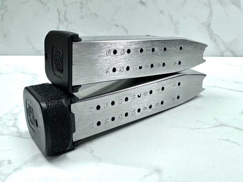 Two magazines lay stacked. The top one has a capacity of 15 bullets and the bottom one can hold 17.