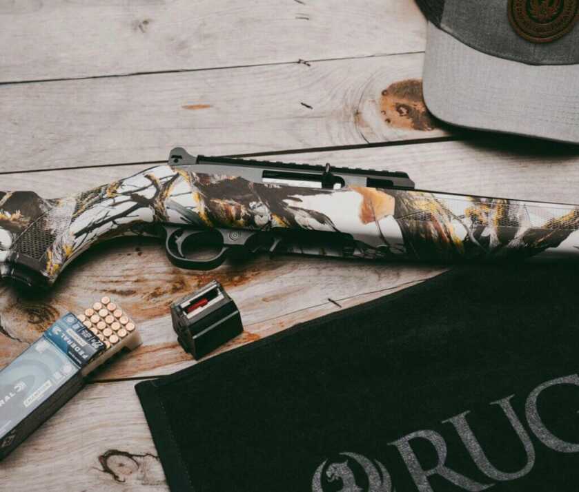A Ruger 10/22 with ammo on a deck. 