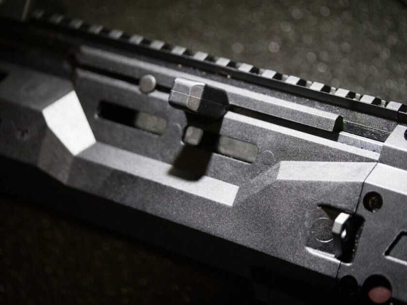 close up of the charging handle in the fore stock. The gun is facing left.