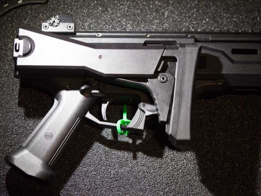 Photo of the right side of the gun laying on a black surface. The stock is folded over the receiver. 
