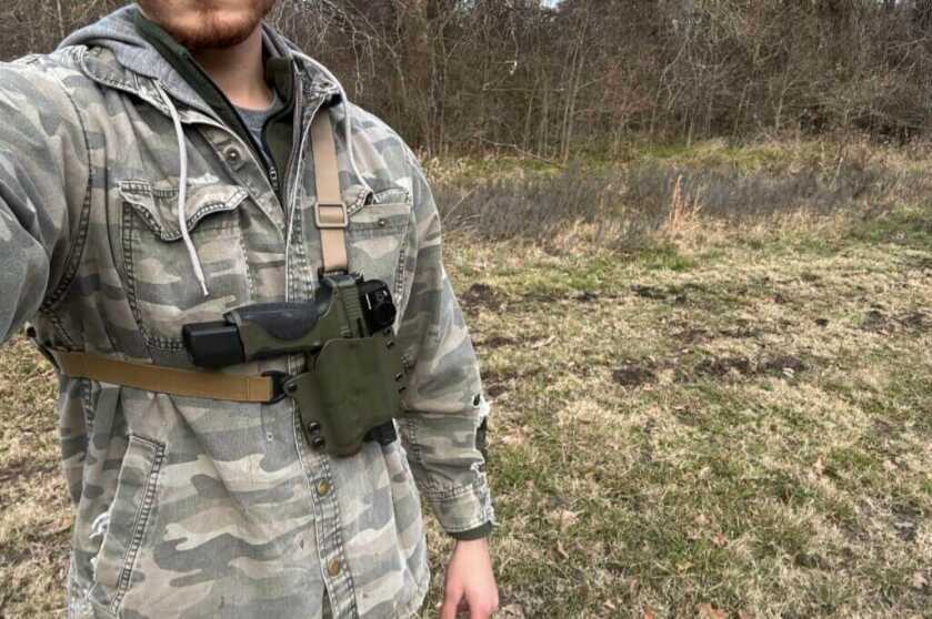 Shooter with Smith and Wesson handgun strapped to his chest outside