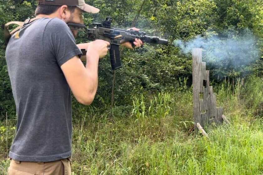 Shooter firing a rifle outside with the Vortex Defender-XL red dot mounted