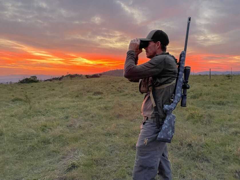 Man looking through spotting scope at sunset