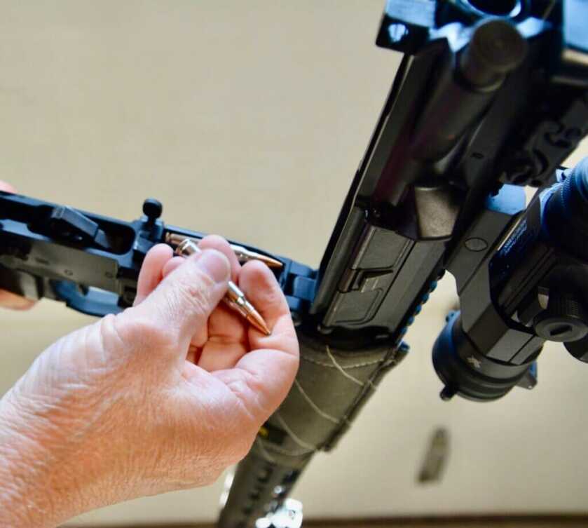 Shooter reloading an open rifle from the top into the magazine